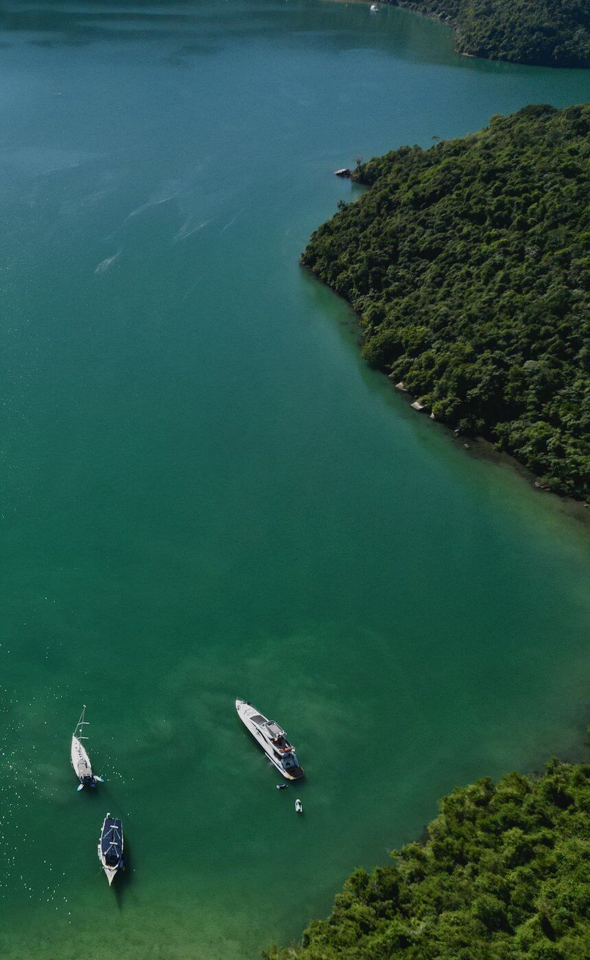 Green-turquoise water and boats by a forested island, Ilha da Cutia, Brazil