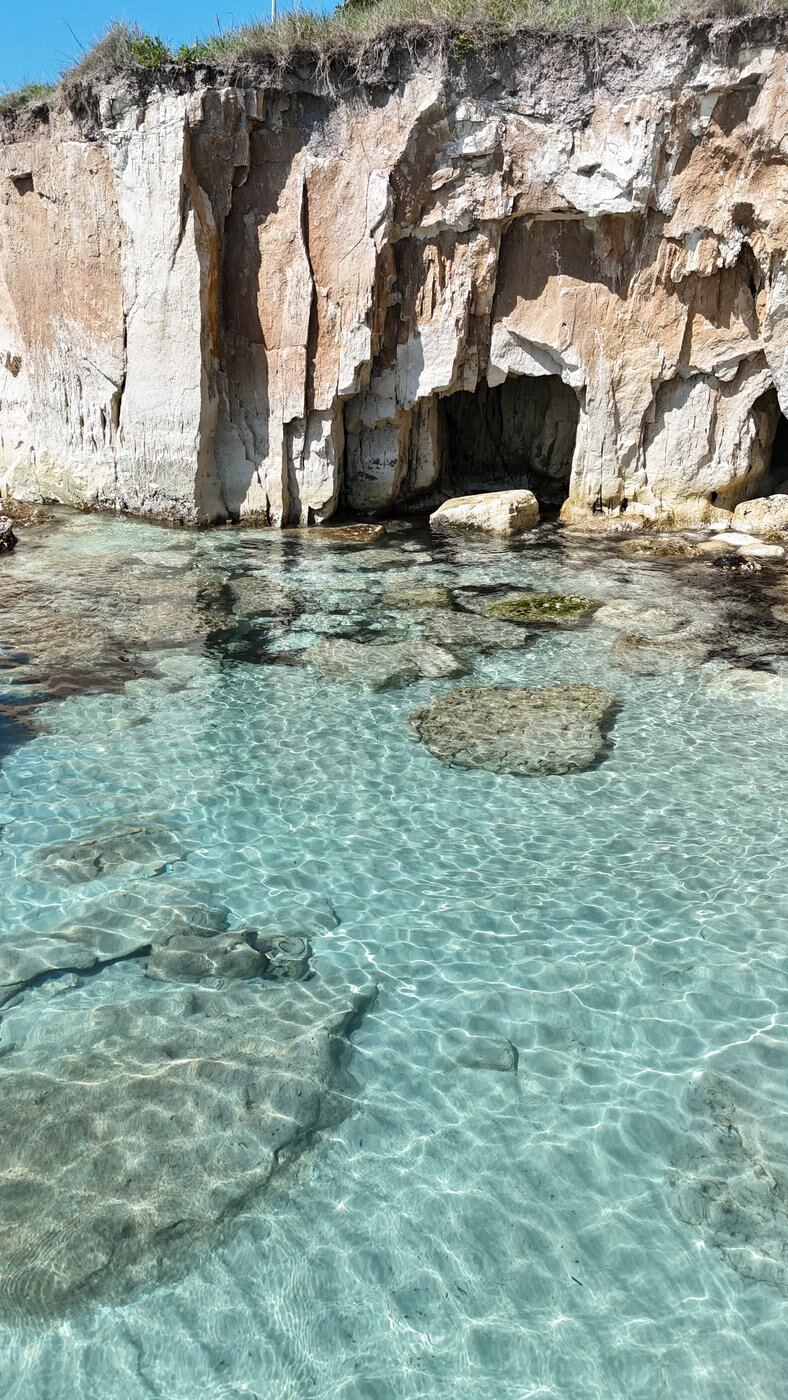 Crystal-clear shallow water by a low cliff, Fontane Bianche, Sicily