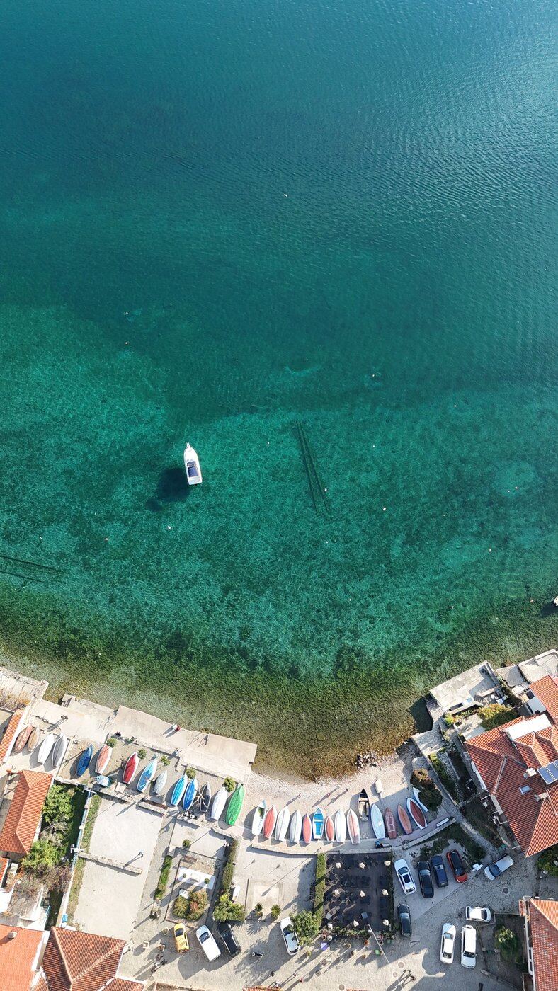 Aerial of clear water and rows of boats along the shore, Lake Ohrid